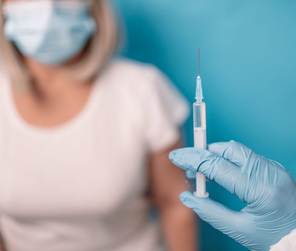 doctor or nurse hand holding syringe with Covid-19 vaccine with inscription booster
